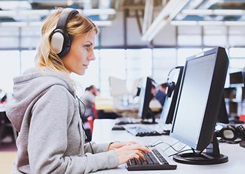 UB English Language Institute student on a computer with headphones